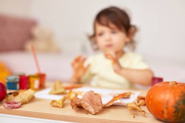 Sonbahar arkaplanı. Mutlu küçük kız çocuğu sonbahar yapraklarını boyuyor. Yapraklara odaklan