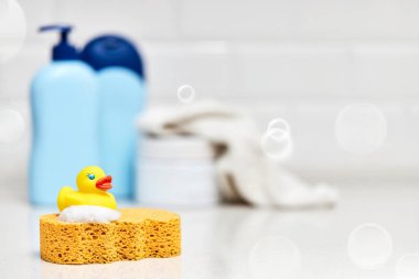Sarı lastik ördek, sabun, banyo zemininde banyo köpüğü, çocuk banyo aksesuarları.
