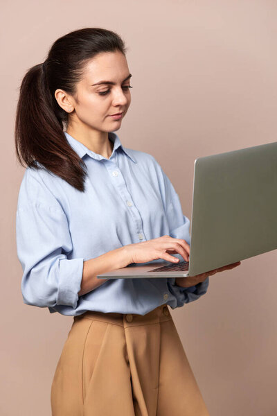 pretty freelancer business woman in blue shirt using laptop for work, e-learning, e-banking or online shopping on beige background