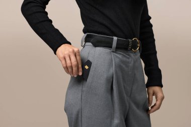 Kadın eli pantolonunun cebine siyah prim kredi kartı koyuyor. Para finans