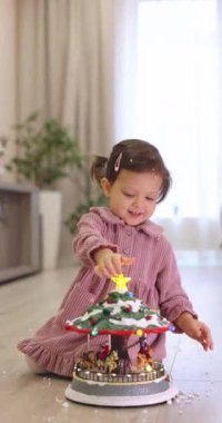 # Mutlu küçük kız çocuğu Noel müzikali serpiştiriyor # # Evde karla süslenmiş atlıkarınca, Mutlu Noeller #