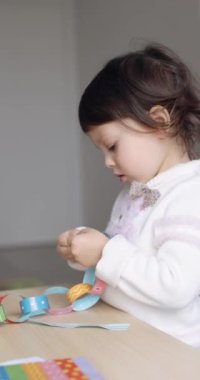 Kağıt çelenk yapıştırıp Noel 'e hazırlanan sevimli küçük bir kız çocuğu. Noel konsepti, çocuk gelişimi