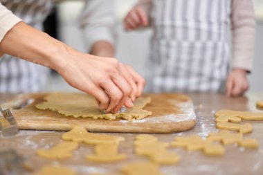 Anne ve küçük kızın elleri mutfakta çiğ zencefilli kurabiye hamuru kesiyor, Noel gelenekleri.