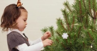 Mutlu küçük kız Noel ağacını tahta oyuncaklarla süslüyor.