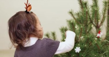 Noel ağacını evde ahşap oyuncaklarla süsleyen küçük tatlı bir kız çocuğu, Noel geleneği.
