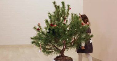 Mutlu küçük kız Noel ağacını tahta oyuncaklarla süslüyor.