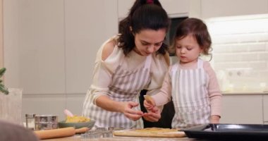 Anne ve küçük kız mutfakta çeşitli şekillerde kurabiyeler kestiler..