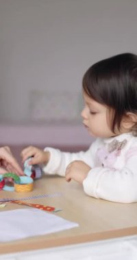 Kağıt çelenk yapıştırıp Noel 'e hazırlanan sevimli küçük bir kız çocuğu. Noel konsepti, çocuk gelişimi