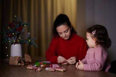 Anne ve küçük kızı akşamları evde Noel hediyelerini paketleyip aile için hediyeler hazırlıyorlar..