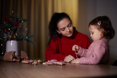 Anne ve küçük kızı akşamları evde Noel hediyelerini paketleyip aile için hediyeler hazırlıyorlar..