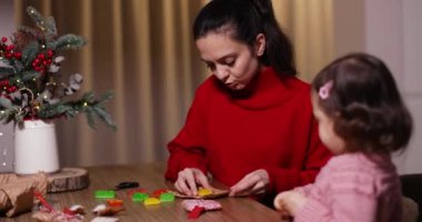 Anne ve küçük kızı birlikte evde Noel hediyelerini paketliyorlar.