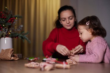 Anne ve küçük kızı akşamları evde Noel hediyelerini paketleyip aile için hediyeler hazırlıyorlar..