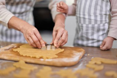 Anne ve küçük kızın elleri mutfakta çiğ zencefilli kurabiye hamuru kesiyor, Noel gelenekleri.