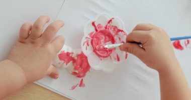 Çocuk eller domuz şeklindeki alçıtaşını pembeye boyuyor. Yaratıcılık. El yapımı oyuncak, üst görünüm