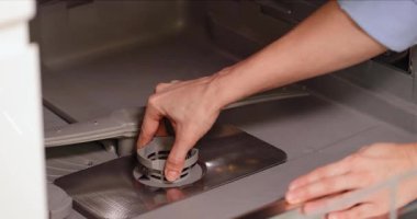 Kadın bulaşık makinesinin içine bulaşık makinesi filtresi koyuyor. Bakım ve hijyen