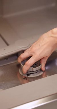 Kadın bulaşık makinesinin içine bulaşık makinesi filtresi koyuyor. Bakım ve hijyen
