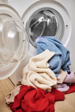 Renkli ve beyaz yün çamaşır makinesi ve açık kapılı çamaşır makinesi. Kapat..