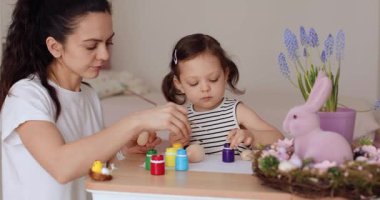 Mutlu anne ve tatlı küçük kız Paskalyayı evde kutlamaya hazırlanıyorlar. Anne ve kızı Paskalya 'dan önce yumurta boyuyor..