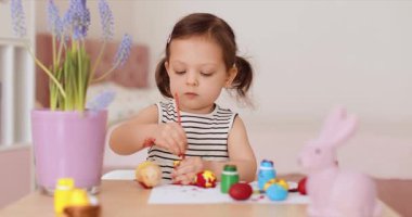 Küçük tatlı kız evde paskalya yumurtası boyuyor. Çocuk Paskalya için hazırlanıyor..