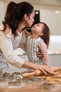 Mutlu anne ve gülümseyen sevimli küçük kız. Ev yapımı hamur işleri için hamuru yuvarlıyor..