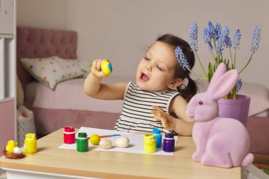 Küçük kız Paskalya yumurtalarını evde boyuyor. Çocuk Paskalya için hazırlanıyor..