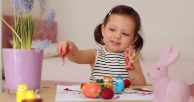 Gülümseyen küçük kız evde paskalya yumurtası boyuyor. Çocuk Paskalya için hazırlanıyor. Mutlu Paskalyalar.