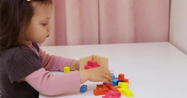 Sevimli küçük kız masanın üzerinde 3 boyutlu yapboz koleksiyonu yapıyor.