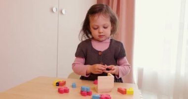 Sevimli küçük kız masanın üzerinde 3 boyutlu yapboz koleksiyonu yapıyor.