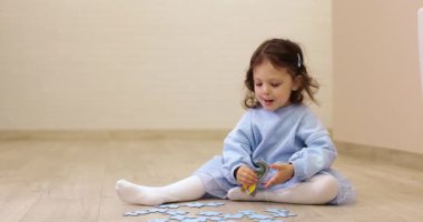 Küçük kız evde yerde bulmaca topluyor, motor becerileri ve mantığı geliştiriyor.