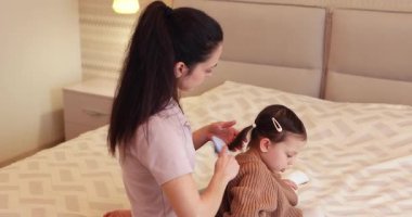 Beyaz tenli anneyi sevmek saç stili küçük kızı evde yatakta yapmak.