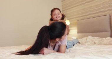 Kahkaha atan anne ve küçük tatlı kızı, sabah yatak odasında eğleniyorlar, özgürlük ve mutluluk.