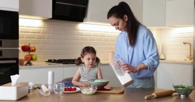 Anne ve küçük sevimli kız mutfakta yemek pişiriyorlar. Anne küçük kızına yemek yapmayı öğretiyor.