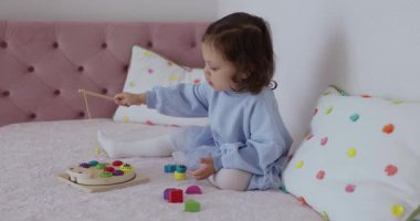 Küçük tatlı kız evde eğitici oyuncaklarla oynuyor, çocuk balık tutuyor.
