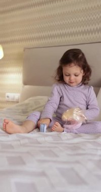 Bebek bebek yatakta oyuncak bebekle oynar, bebek saçlarını tarar.