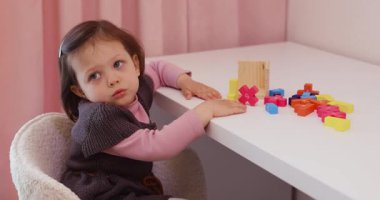 Sevimli küçük kız masanın üzerinde 3 boyutlu yapboz koleksiyonu yapıyor.