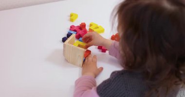 Sevimli küçük kız masanın üstünde 3D yapboz topluyor.