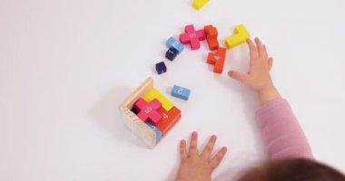 Küçük kız çocuğunun yakın plan fotoğrafları masanın üstünde 3D bulmaca topluyor.