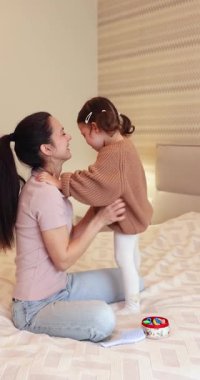 Kahkaha atan anne ve küçük tatlı kızı, sabah yatak odasında eğleniyorlar, özgürlük ve mutluluk.