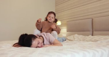 Kahkaha atan anne ve küçük tatlı kızı, sabah yatak odasında eğleniyorlar, özgürlük ve mutluluk.