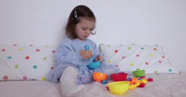 Güzel motor becerileri ve mantığı geliştirmek için renk ayırıcı ile oynayan tatlı bir kız. Evde erken çocuk gelişimi