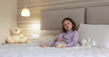 Bebek bebek yatakta oyuncak bebekle oynar, bebek saçlarını tarar.