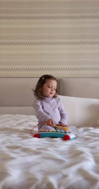 Sevimli küçük kız çocuğu 3 yaşında rahat yatak odasında ksilofon çalıyor.