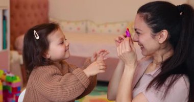 Annesinin renkli kille oynayıp eğlendiği komik küçük bir kız çocuğu. Plastiksin. Hamur oyna