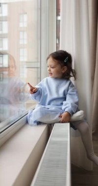 Küçük bebek pencereden dışarı bakıyor, çocuk evde tek başına duruyor, şirin bebek ailesini bekliyor..