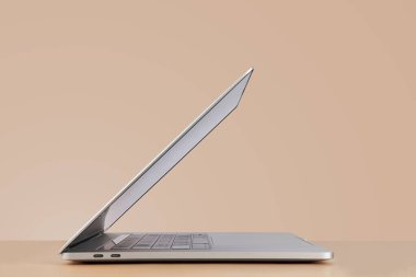 Bej arkaplanda açık dizüstü bilgisayarın yan görünümü