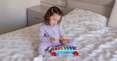 Sevimli küçük kız çocuğu 3 yaşında rahat yatak odasında ksilofon çalıyor.
