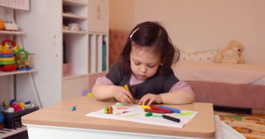 Evdeki beyaz kağıda kurşun kalemle resim çizen küçük şirin bir kız. Yaratıcı aktivite.