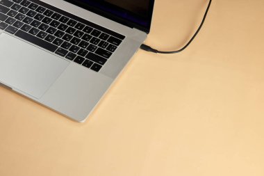 Bej arka planda dizüstü bilgisayara bağlı kablo, yakın plan. Pil dizüstü bilgisayarı yükleniyor, boşluğu kopyala