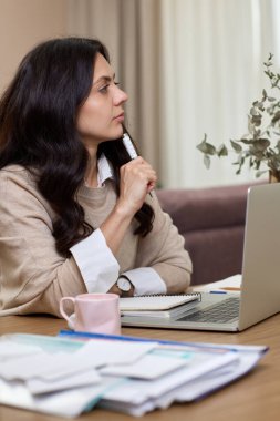 Evde çalışırken dizüstü bilgisayar kullanan gömlekli güzel bir kadın.