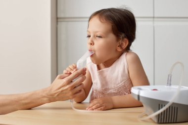 Kadın, evde hasta bir çocuğa solunum yapıyor.